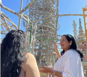 The image shows a woman and a girl riding a roller coaster. The woman and the girl are both visible in the photo. The background of the image shows the sky. The woman is wearing clothing suitable for a theme park ride.